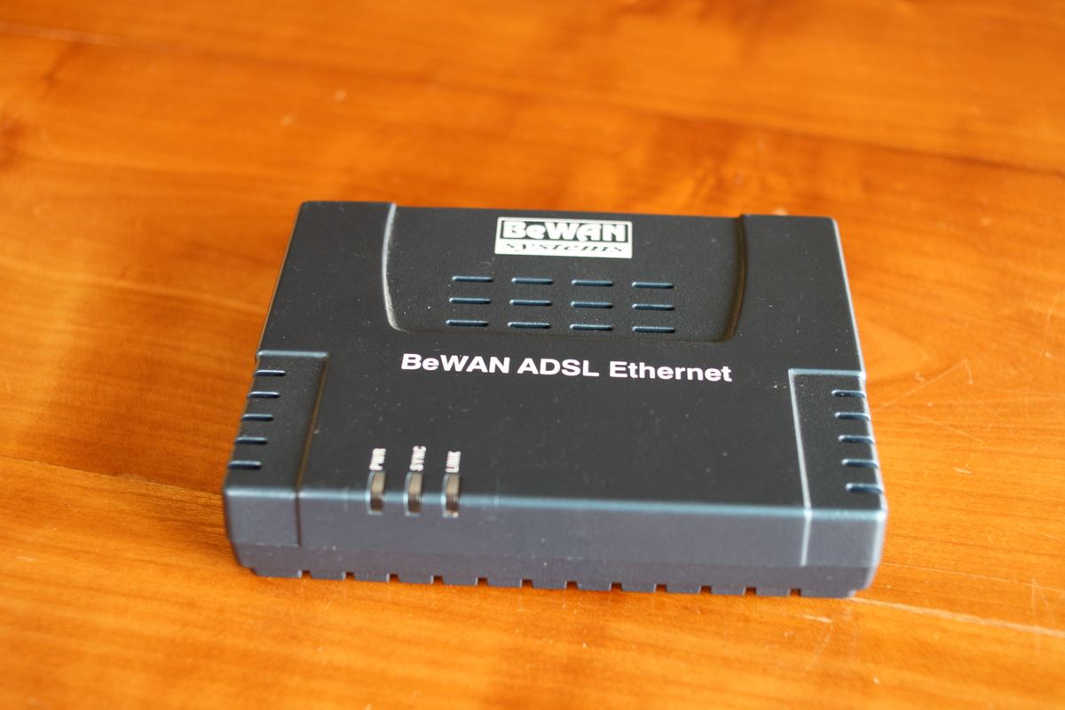 Ancien modem ADSL noir à voyants posé sur une table en bois