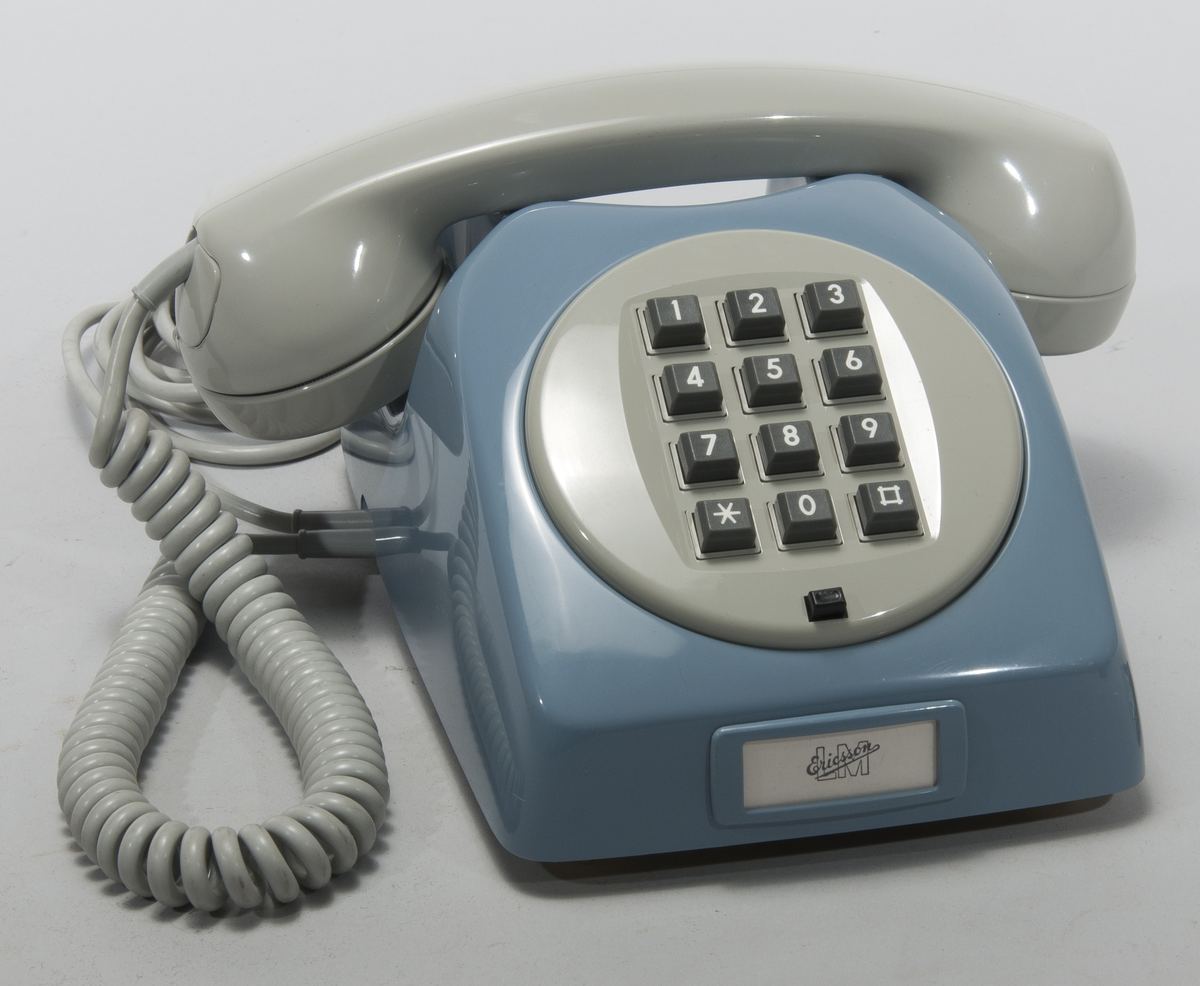 Ancien téléphone fixe bleu à touches avec son combiné gris et son cordon spiralé